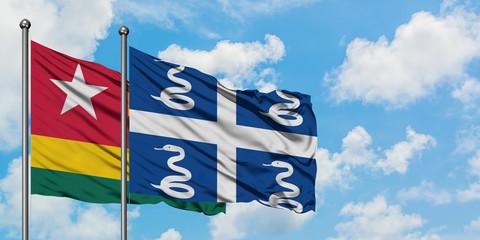 Togo and Martinique flag waving in the wind against white cloudy blue sky together. Diplomacy...
