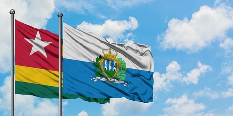 Togo and San Marino flag waving in the wind against white cloudy blue sky together. Diplomacy concept, international relations.