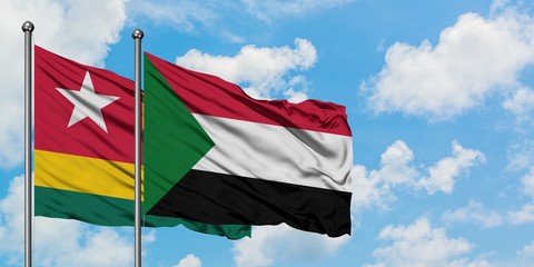 Togo and Sudan flag waving in the wind against white cloudy blue sky together. Diplomacy concept, international relations.