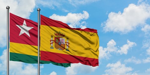 Togo and Spain flag waving in the wind against white cloudy blue sky together. Diplomacy concept, international relations.