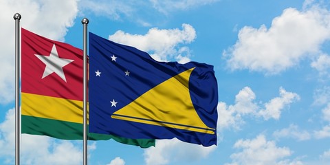 Togo and Tokelau flag waving in the wind against white cloudy blue sky together. Diplomacy concept, international relations.