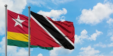 Togo and Trinidad And Tobago flag waving in the wind against white cloudy blue sky together. Diplomacy concept, international relations.