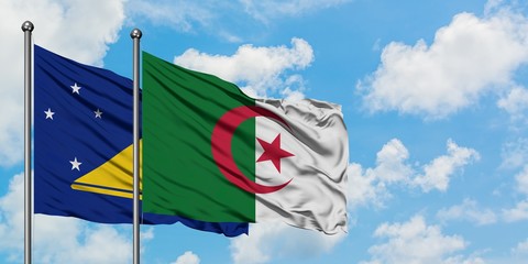 Tokelau and Algeria flag waving in the wind against white cloudy blue sky together. Diplomacy...