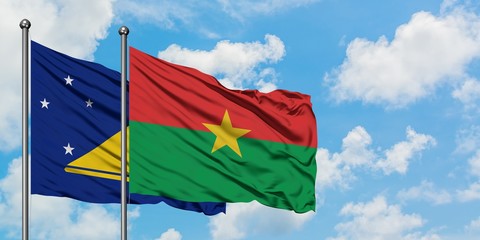 Tokelau and Burkina Faso flag waving in the wind against white cloudy blue sky together. Diplomacy concept, international relations.