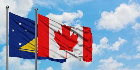 Tokelau and Canada flag waving in the wind against white cloudy blue sky together. Diplomacy concept, international relations.