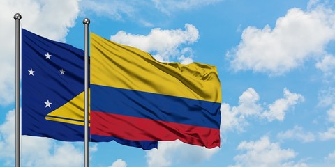 Tokelau and Colombia flag waving in the wind against white cloudy blue sky together. Diplomacy concept, international relations.