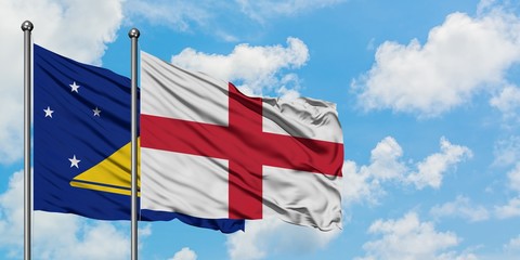 Tokelau and England flag waving in the wind against white cloudy blue sky together. Diplomacy concept, international relations.