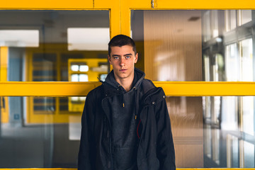 portrait of a smiling young man in front of yellow windows