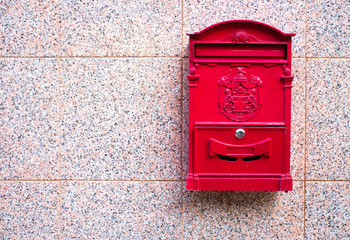 Classic red mailbox on a stone wall.