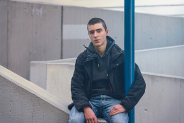 Obraz premium portrait of a casual young man in sitting on a concrete wall