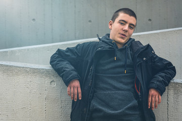 portrait of a smiling young man in leaning against a concrete wall