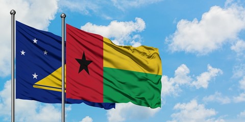 Tokelau and Guinea Bissau flag waving in the wind against white cloudy blue sky together. Diplomacy concept, international relations.