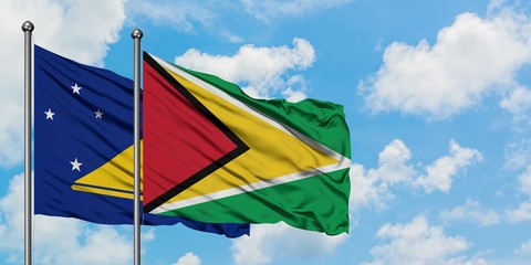 Tokelau and Guyana flag waving in the wind against white cloudy blue sky together. Diplomacy concept, international relations.