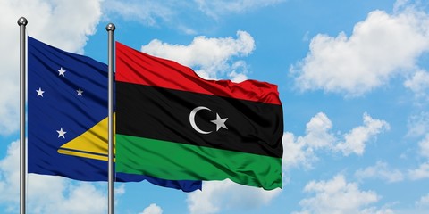 Tokelau and Libya flag waving in the wind against white cloudy blue sky together. Diplomacy concept, international relations.