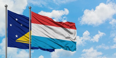 Tokelau and Luxembourg flag waving in the wind against white cloudy blue sky together. Diplomacy concept, international relations.
