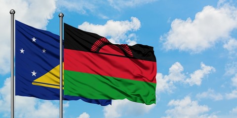 Tokelau and Malawi flag waving in the wind against white cloudy blue sky together. Diplomacy concept, international relations.