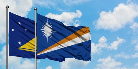 Tokelau and Marshall Islands flag waving in the wind against white cloudy blue sky together....