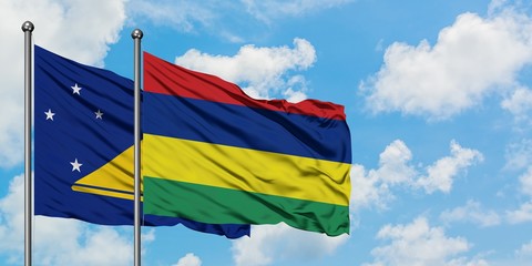 Tokelau and Mauritius flag waving in the wind against white cloudy blue sky together. Diplomacy concept, international relations.
