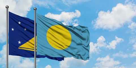 Tokelau and Palau flag waving in the wind against white cloudy blue sky together. Diplomacy concept, international relations.