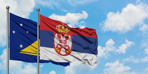 Tokelau and Serbia flag waving in the wind against white cloudy blue sky together. Diplomacy concept, international relations.