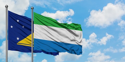 Tokelau and Sierra Leone flag waving in the wind against white cloudy blue sky together. Diplomacy concept, international relations.