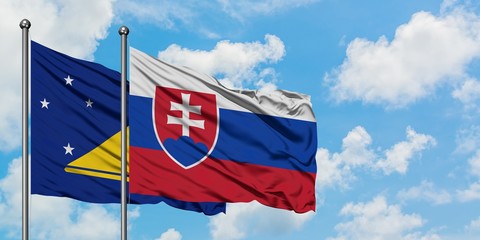 Tokelau and Slovakia flag waving in the wind against white cloudy blue sky together. Diplomacy concept, international relations.