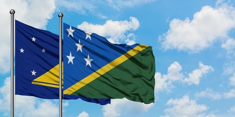 Tokelau and Solomon Islands flag waving in the wind against white cloudy blue sky together....