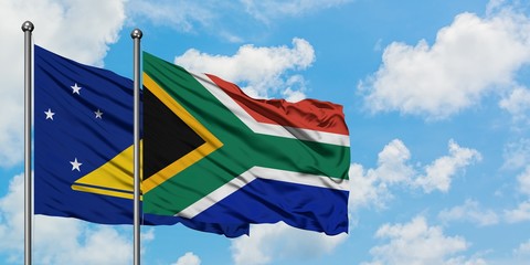 Tokelau and South Africa flag waving in the wind against white cloudy blue sky together. Diplomacy concept, international relations.