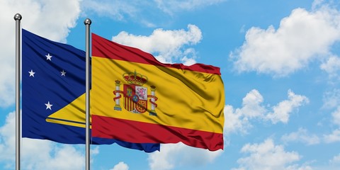 Tokelau and Spain flag waving in the wind against white cloudy blue sky together. Diplomacy concept, international relations.