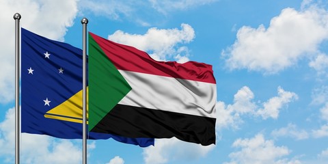 Tokelau and Sudan flag waving in the wind against white cloudy blue sky together. Diplomacy...