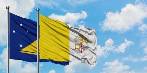 Tokelau and Vatican City flag waving in the wind against white cloudy blue sky together. Diplomacy concept, international relations.