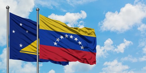 Tokelau and Venezuela flag waving in the wind against white cloudy blue sky together. Diplomacy concept, international relations.