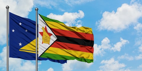 Tokelau and Zimbabwe flag waving in the wind against white cloudy blue sky together. Diplomacy concept, international relations.