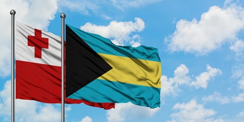 Tonga and Bahamas flag waving in the wind against white cloudy blue sky together. Diplomacy concept, international relations.