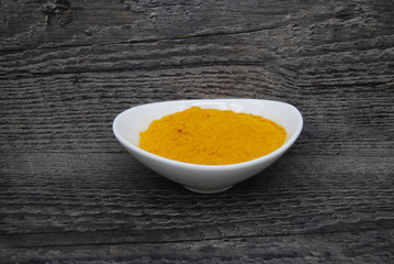 Fresh Turmeric Powder in a dish with a rustic background