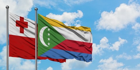 Tonga and Comoros flag waving in the wind against white cloudy blue sky together. Diplomacy...