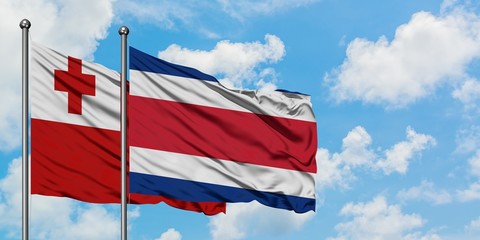 Tonga and Costa Rica flag waving in the wind against white cloudy blue sky together. Diplomacy...