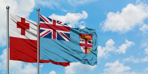 Tonga and Fiji flag waving in the wind against white cloudy blue sky together. Diplomacy concept, international relations.