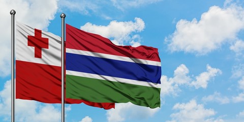 Tonga and Gambia flag waving in the wind against white cloudy blue sky together. Diplomacy concept, international relations.