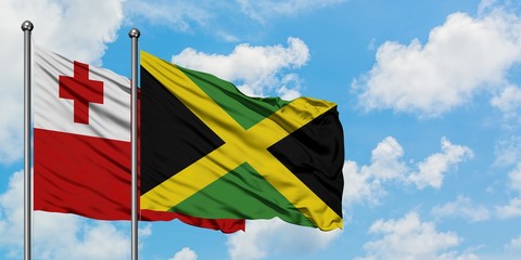 Tonga and Jamaica flag waving in the wind against white cloudy blue sky together. Diplomacy concept, international relations.