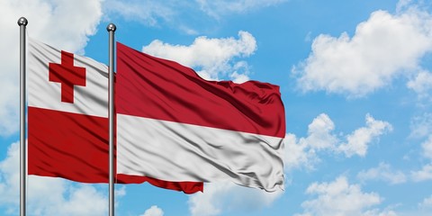 Tonga and Monaco flag waving in the wind against white cloudy blue sky together. Diplomacy concept, international relations.