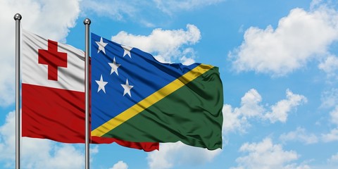 Tonga and Solomon Islands flag waving in the wind against white cloudy blue sky together. Diplomacy...