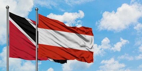 Trinidad And Tobago and Austria flag waving in the wind against white cloudy blue sky together. Diplomacy concept, international relations.