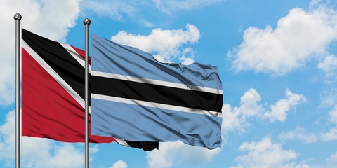 Trinidad And Tobago and Botswana flag waving in the wind against white cloudy blue sky together. Diplomacy concept, international relations.