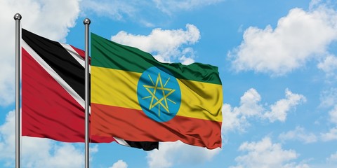 Trinidad And Tobago and Ethiopia flag waving in the wind against white cloudy blue sky together. Diplomacy concept, international relations.