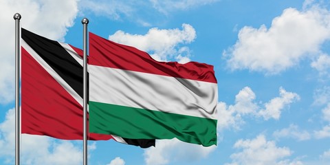 Trinidad And Tobago and Hungary flag waving in the wind against white cloudy blue sky together. Diplomacy concept, international relations.