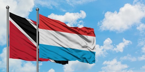 Trinidad And Tobago and Luxembourg flag waving in the wind against white cloudy blue sky together. Diplomacy concept, international relations.