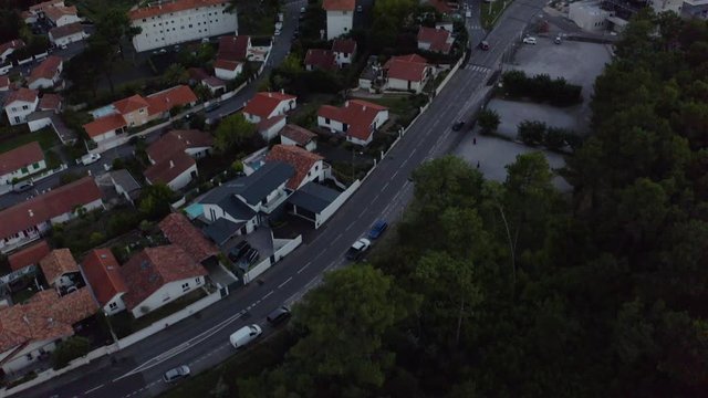 Aerial Drone Shot over french houses with orange tiled roofs in Basque country, France. French city in 4K UHD, the day. Mountains background in blue orange sunset sky.