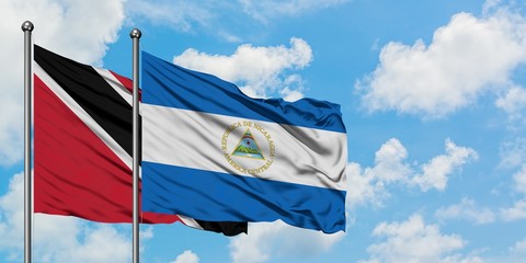 Trinidad And Tobago and Nicaragua flag waving in the wind against white cloudy blue sky together. Diplomacy concept, international relations.