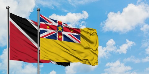 Trinidad And Tobago and Niue flag waving in the wind against white cloudy blue sky together....
